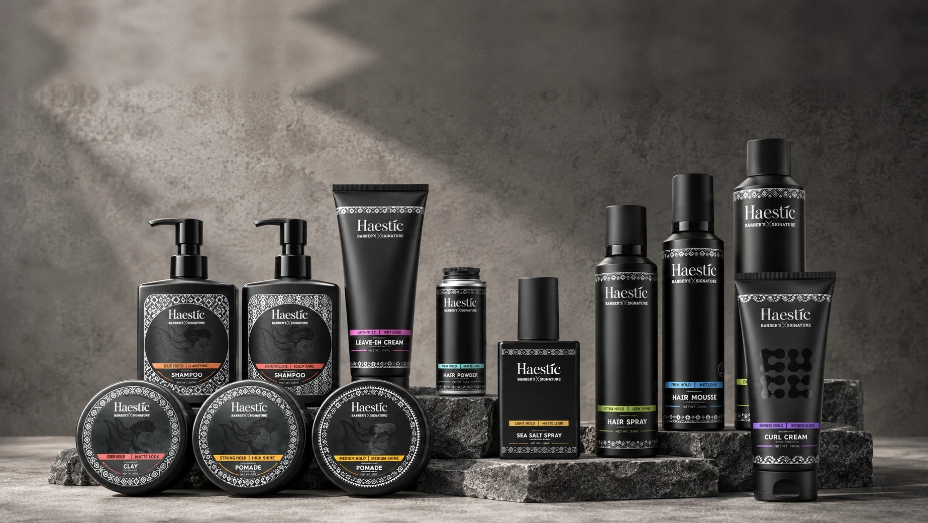 The Haestic Barber’s Signature range — shampoos, clay, pomades, leave-in cream, hair powder, sea salt spray, hair spray, hair mousse and curl cream — arranged on stone steps