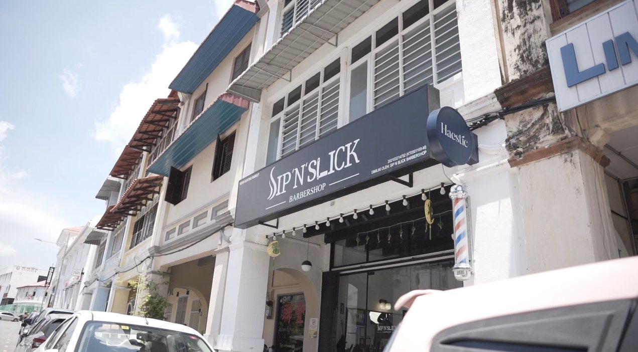 Sip N Slick Barbershop storefront with its navy signboard and a Haestic round sign