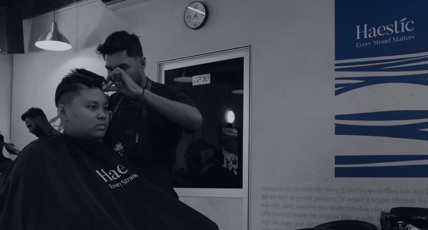 Barber trimming a client's hair at a Haestic barbershop