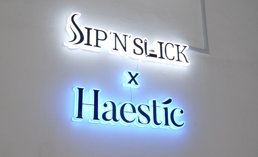 Illuminated Sip N Slick x Haestic neon sign on a white wall