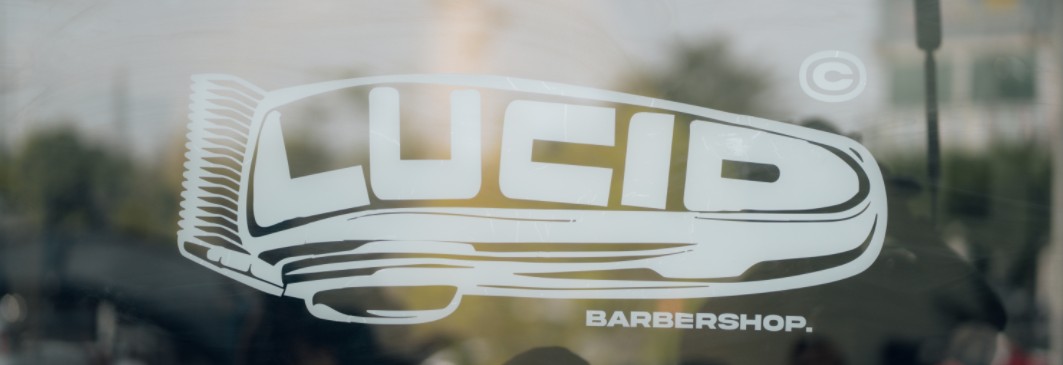 Lucid Barbershop logo in white on a glass window, with a clipper-shaped wordmark