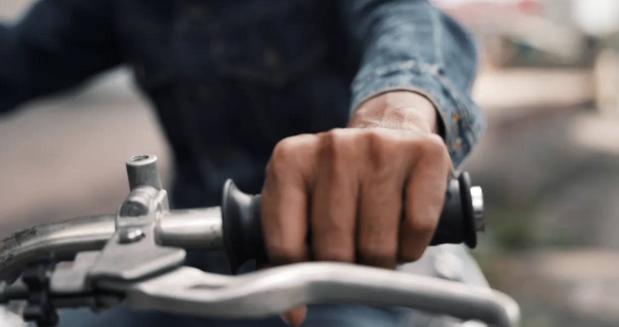 Hand gripping the handlebar of a motorbike
