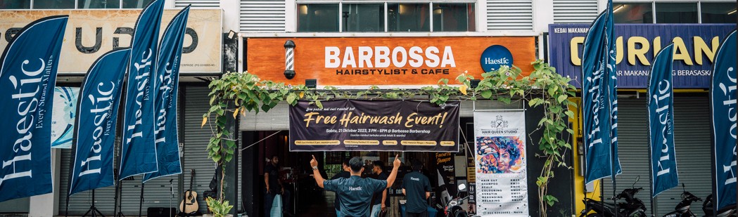 Barbossa Hairstylist & Cafe storefront with Haestic flags and a Free Hairwash Event banner