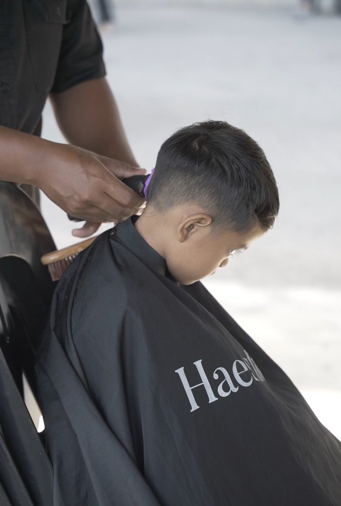 Young boy getting a fade under a Haestic cape